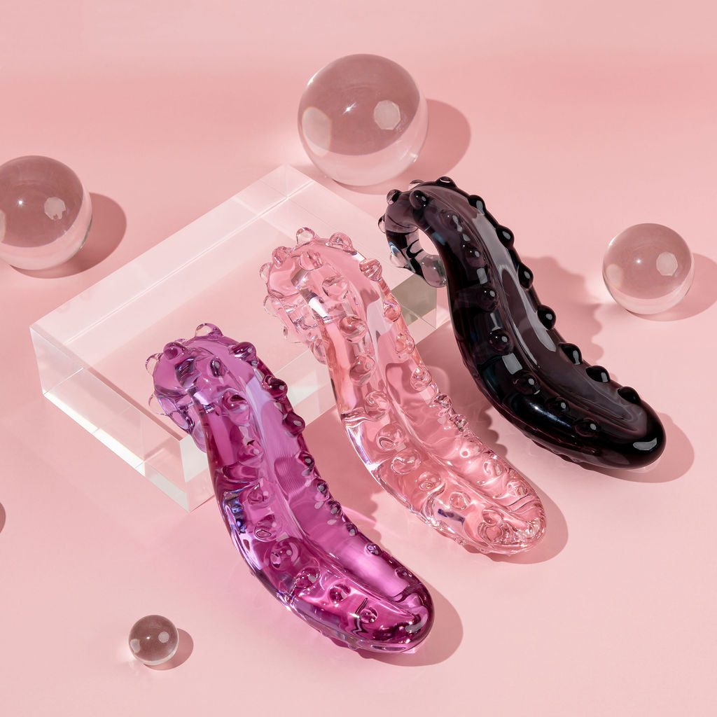 3 Sacred Squirter wands showing different colours available. Lilac, pink and Midnight Black Ink. Glass Pleasure wand with ridges pictured on acrylic block with bubbles.